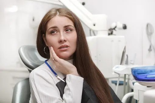 Patient experiencing tooth pain while seated in a dental clinic